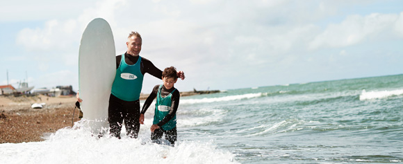 Vater und Sohn beim Wellenreiten bei Westjütland