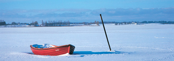Ruderboot auf zugefrorenem Fjord im Winter auf Westseeland